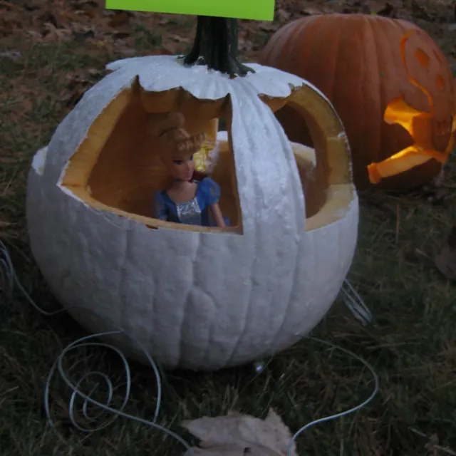 A white pumpkin carved into Cinderella’s carriage, with a Cinderella doll inside
